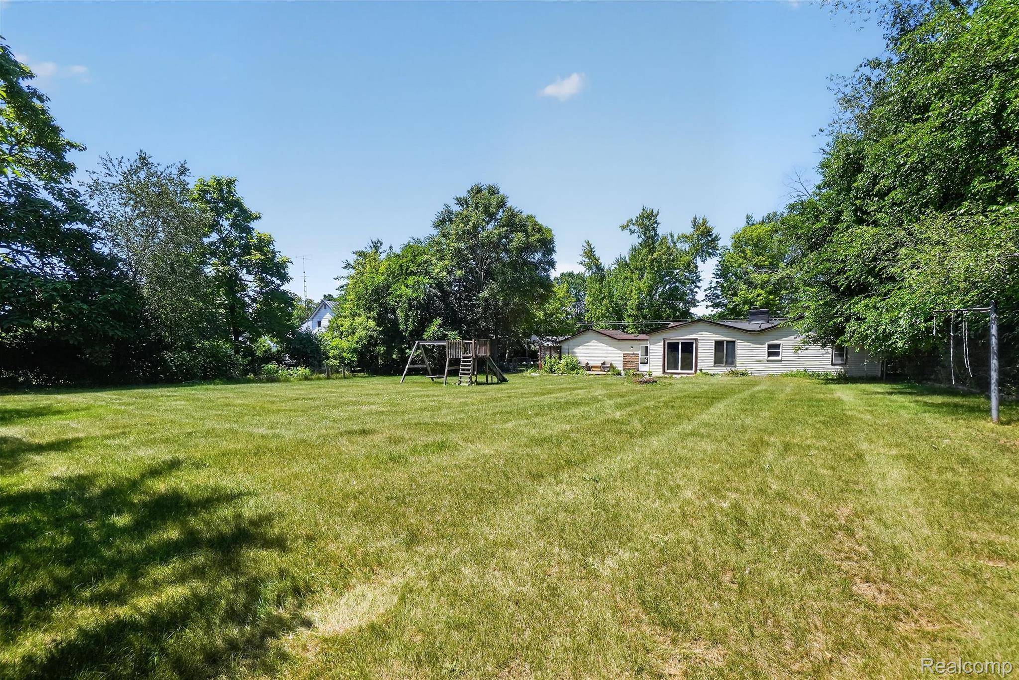 508 Deland Road Flushing, MI 48433 - Photo 32 of 38 Expansive backyard featuring a manicured lawn, mature trees providing natural screening, and a single-story residence with a light-colored exterior