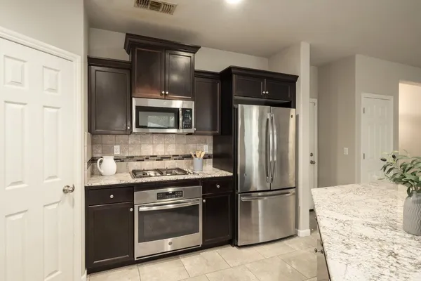 a kitchen with stainless steel appliances granite countertop a refrigerator stove and microwave