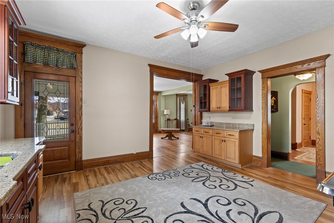 1011 Parriott Avenue Moundsville, WV 26041 - Photo 14 of 44 Kitchen with glass insert cabinets, light stone countertops, light wood-style flooring, arched walkways, and ceiling fan