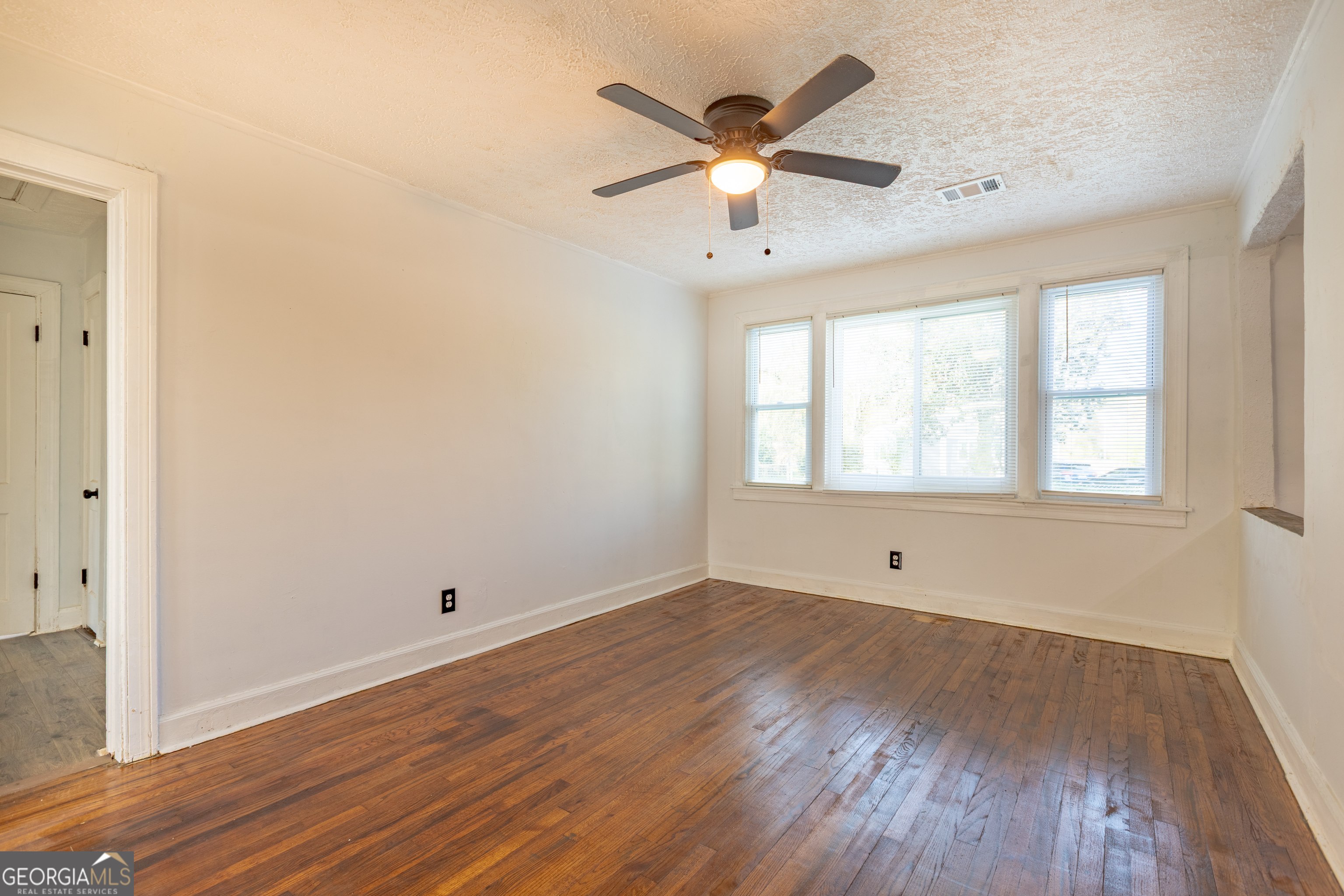 1102 Calvin Avenue Columbus, GA 31903 - Photo 4 of 18 an empty room with wooden floor chandelier fan and windows