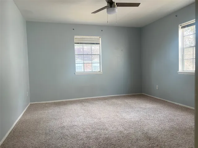 an empty room with windows and fan