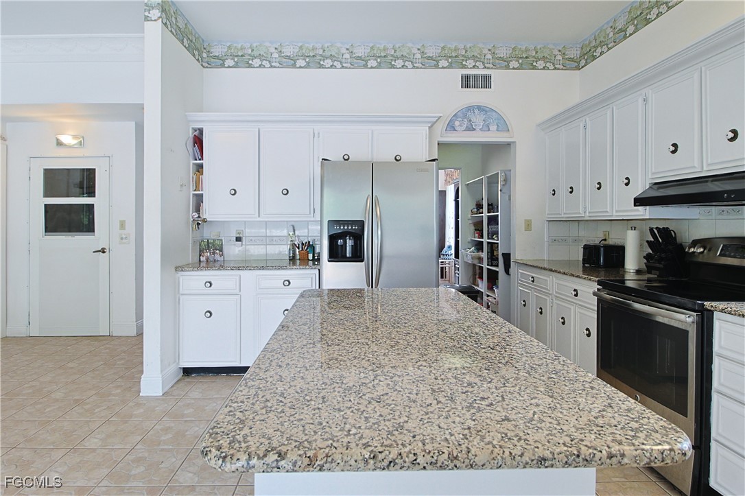 21810 Pearl Street Alva, FL 33920 - Photo 27 of 50 a large kitchen with kitchen island granite countertop a sink white cabinets stainless steel appliances and a counter space