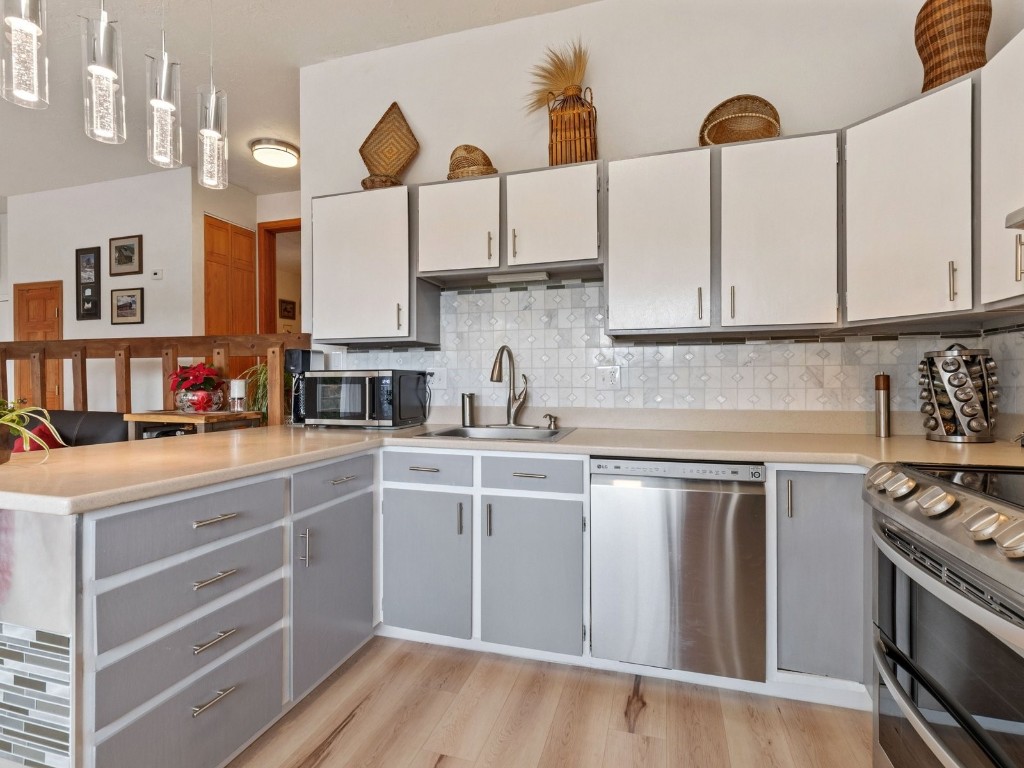 9825 Ryan Gulch Road, Unit B108 Silverthorne, CO 80498 - Photo 7 of 26 a kitchen with stainless steel appliances granite countertop a sink and cabinets with wooden floor