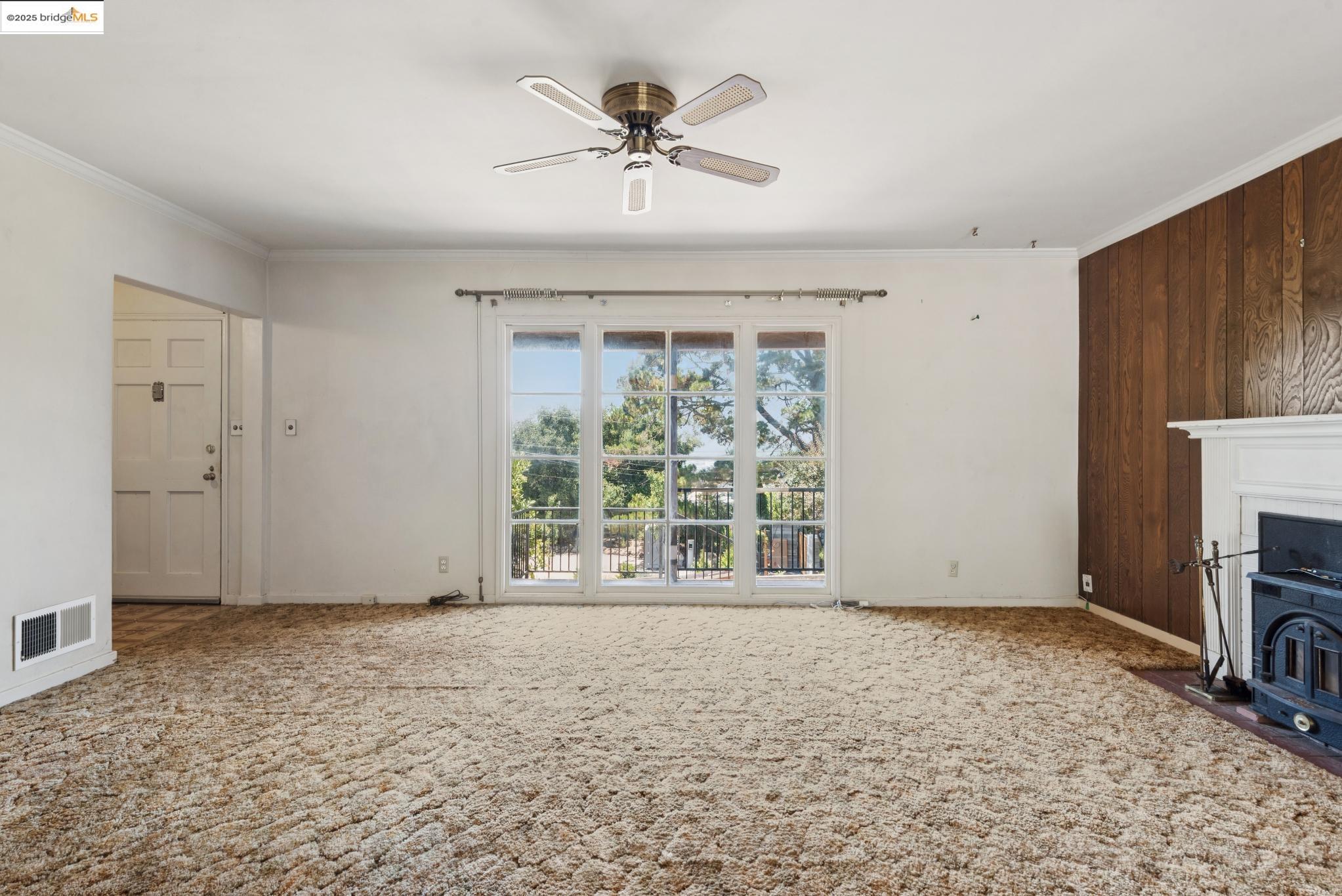4751 Lincoln Avenue Oakland, CA 94602 - Photo 12 of 60 Unfurnished living room with ornamental molding, a ceiling fan, carpet, and wood walls