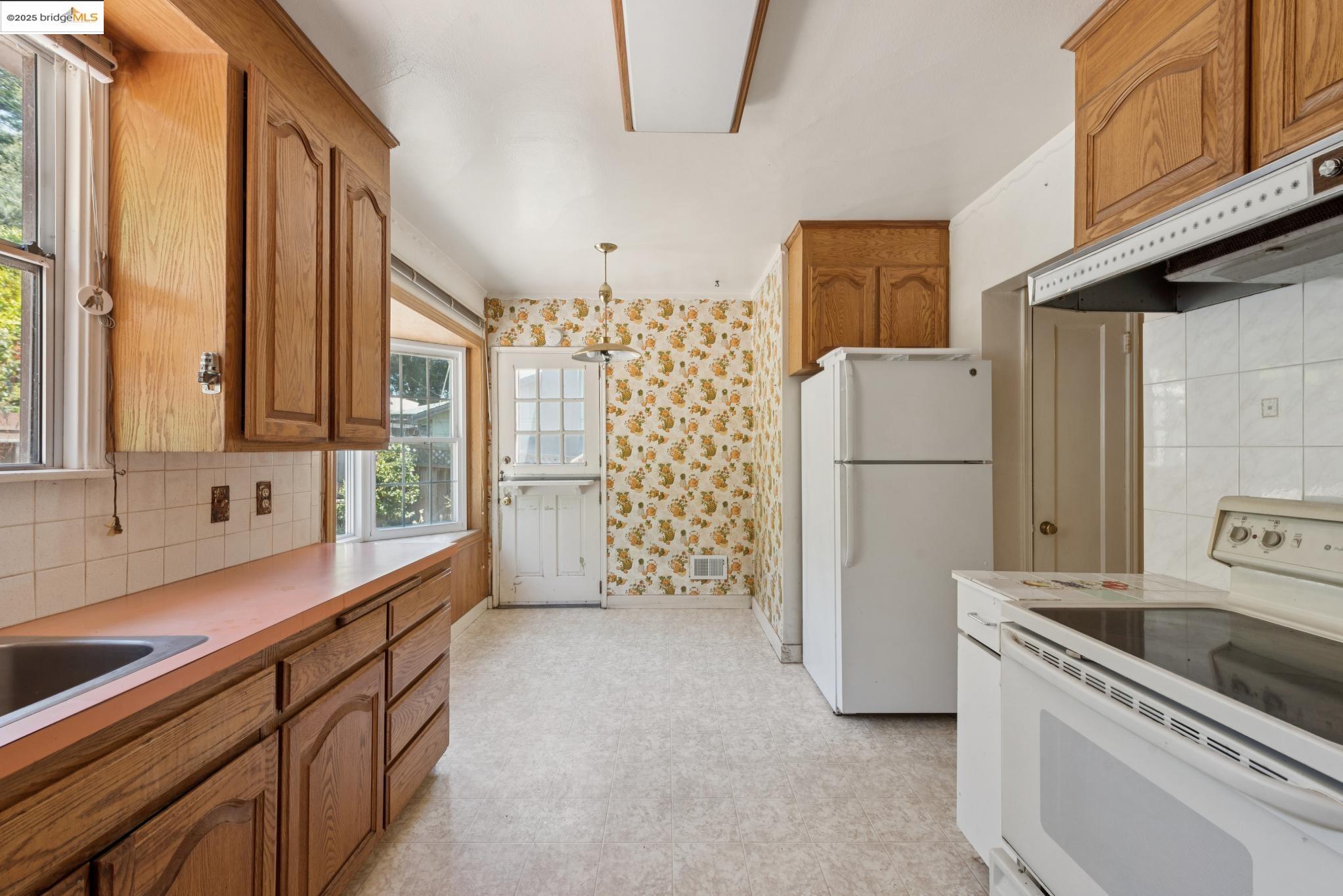 4751 Lincoln Avenue Oakland, CA 94602 - Photo 19 of 60 Kitchen with decorative backsplash, white appliances, light flooring, wallpapered walls, and light countertops