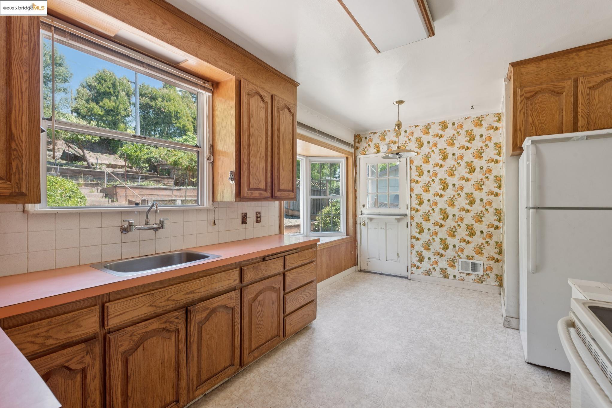 4751 Lincoln Avenue Oakland, CA 94602 - Photo 20 of 60 Kitchen with decorative light fixtures, light countertops, brown cabinets, white appliances, and tasteful backsplash