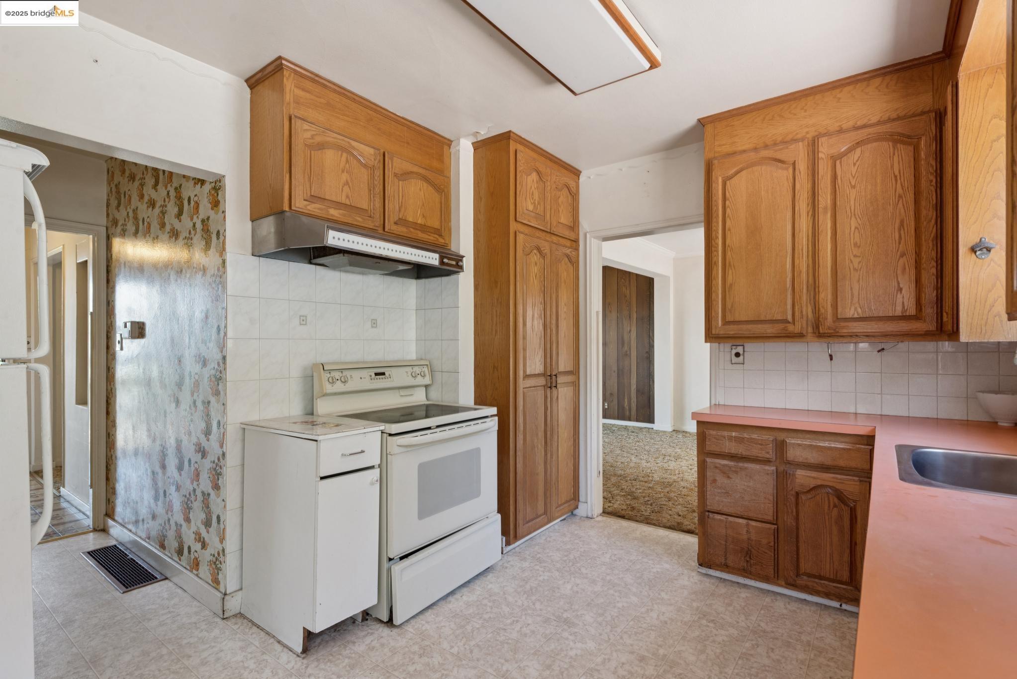 4751 Lincoln Avenue Oakland, CA 94602 - Photo 22 of 60 Kitchen featuring white appliances, tasteful backsplash, brown cabinets, light countertops, and under cabinet range hood