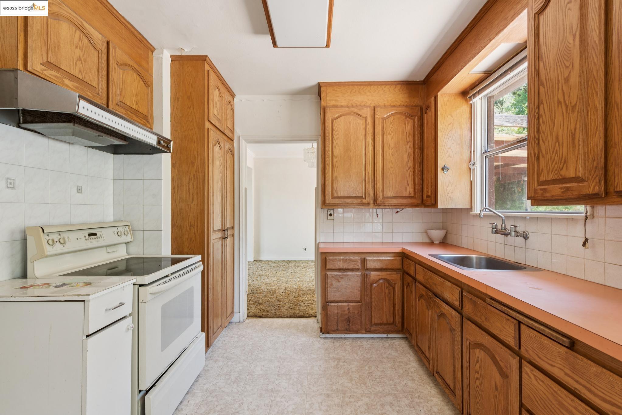 4751 Lincoln Avenue Oakland, CA 94602 - Photo 23 of 60 Kitchen featuring white electric stove, backsplash, under cabinet range hood, brown cabinets, and light countertops