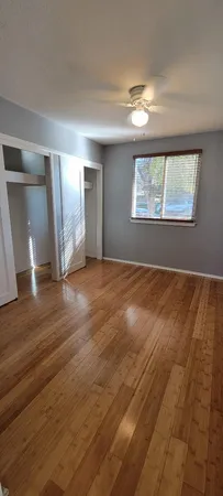 an empty room with a chandelier fan and windows