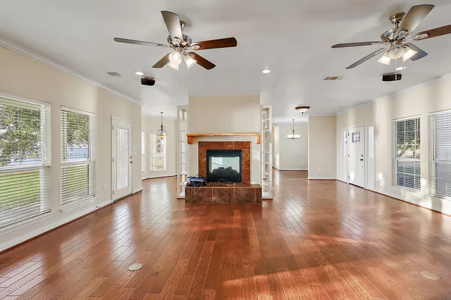 a view of a room with wooden floor fireplace and windows