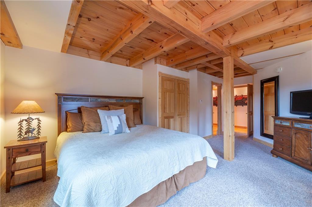1202 Tiger Road Breckenridge, CO 80424 - Photo 13 of 35 a bedroom with a large bed and a chandelier