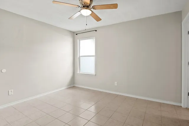 an empty room with windows and fan