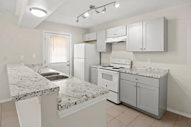 a kitchen with granite countertop a sink stove and refrigerator