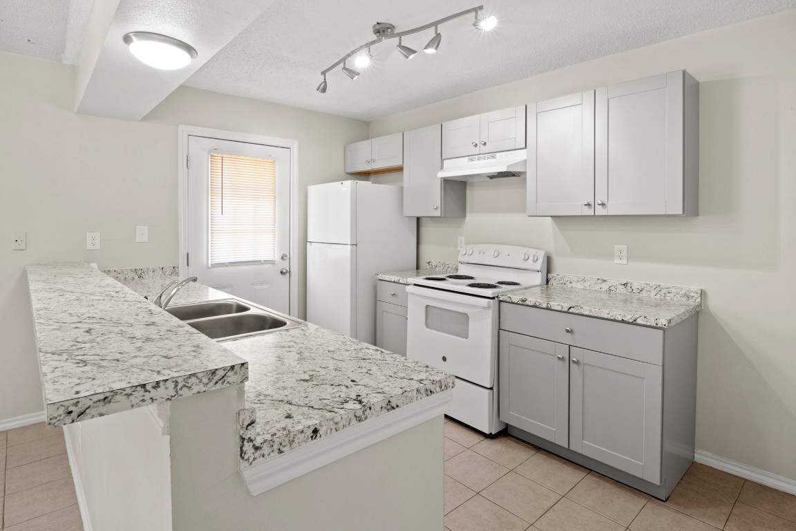 23393 Nameless Road, Unit 160 Leander, TX 78641 - Photo 9 of 20 a kitchen with granite countertop a sink stove and refrigerator