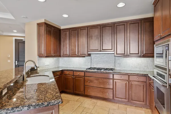 a kitchen with kitchen island granite countertop stainless steel appliances a sink a stove a microwave and cabinets