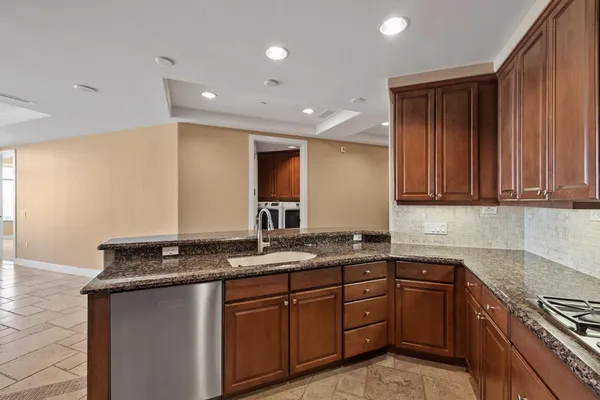 a kitchen with granite countertop stainless steel appliances a sink stove and cabinets