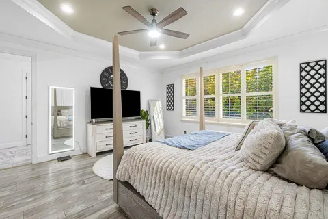 a bedroom with a bed large window and a flat screen tv