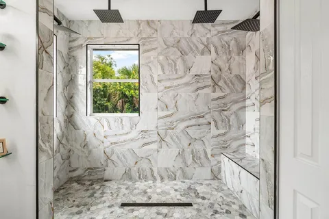 a bathroom with a granite countertop shower and a window