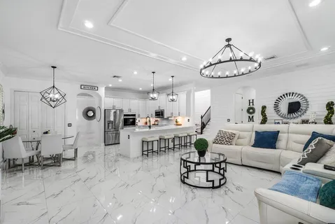 a living room with furniture kitchen view and a chandelier