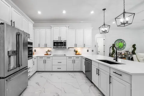 a kitchen with kitchen island granite countertop stainless steel appliances a sink a stove a refrigerator and cabinets