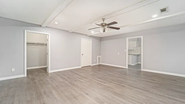 an empty room with wooden floor and windows