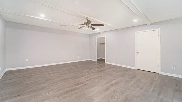 an empty room with wooden floor and ceiling fan