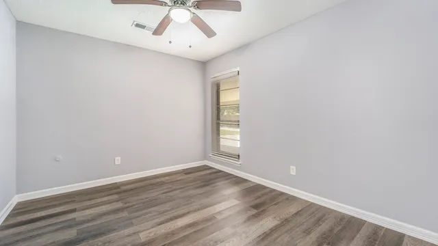 an empty room with a window and wooden floor