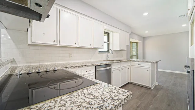 a kitchen with granite countertop white cabinets white appliances a sink and a window