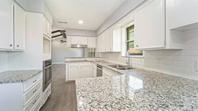 a kitchen with granite countertop white cabinets and white appliances