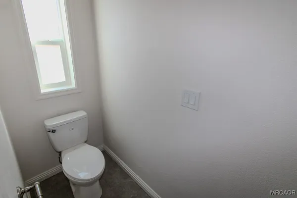 a white toilet sitting in a bathroom next to a window