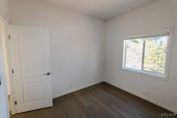 an empty room with wooden floor and window