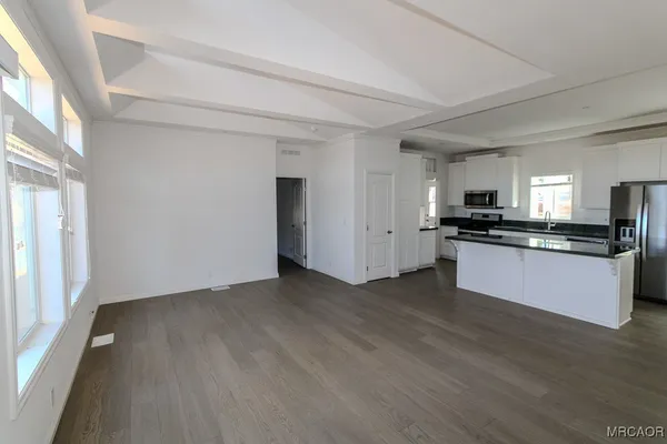 a view of kitchen with granite countertop stainless steel appliances counter space and wooden floor