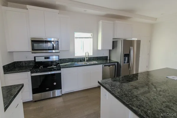 a kitchen with granite countertop a sink and stainless steel appliances