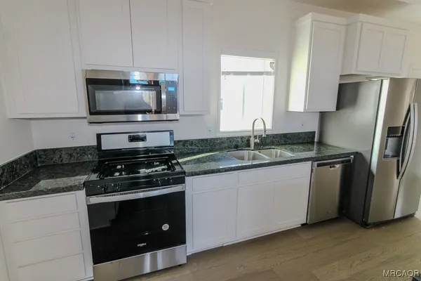 a kitchen with granite countertop a sink stove and refrigerator