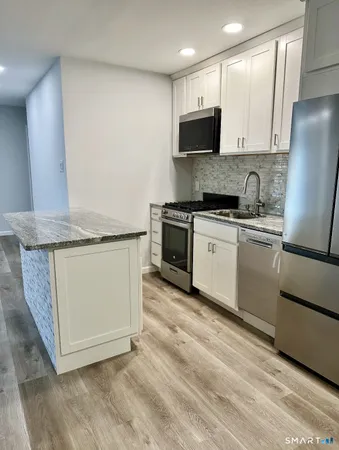 a kitchen with stainless steel appliances granite countertop a stove a sink and a microwave