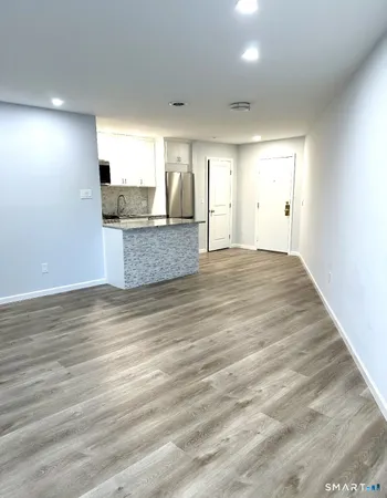 a view of kitchen and empty room with wooden floor