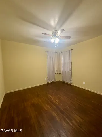 an empty room with a ceiling fan and wooden floor