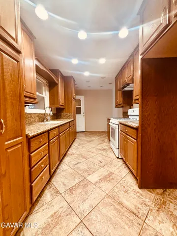 a large kitchen with stainless steel appliances kitchen island granite countertop a refrigerator and cabinets