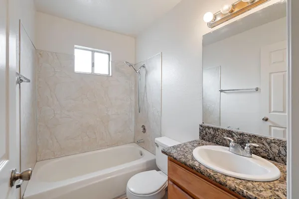 a bathroom with a granite countertop sink toilet tub and shower