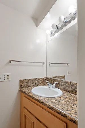 a bathroom with a granite countertop sink and a mirror