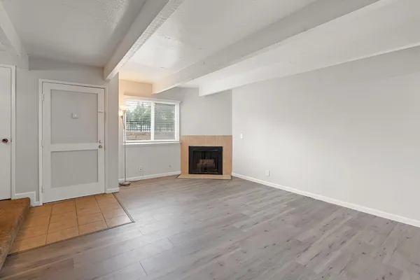an empty room with wooden floor fireplace and windows