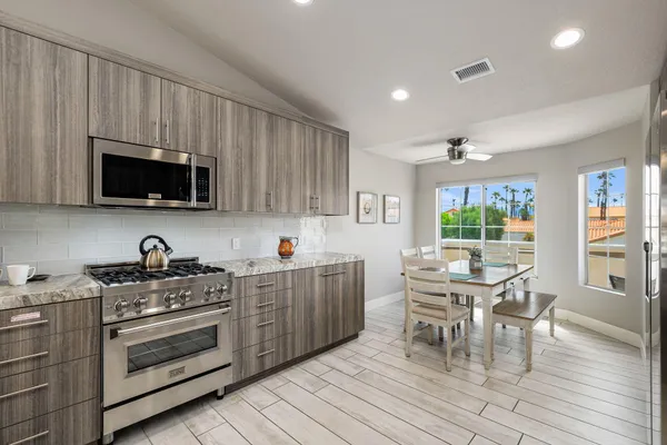 a kitchen with granite countertop a stove top oven a sink a dining table and chairs