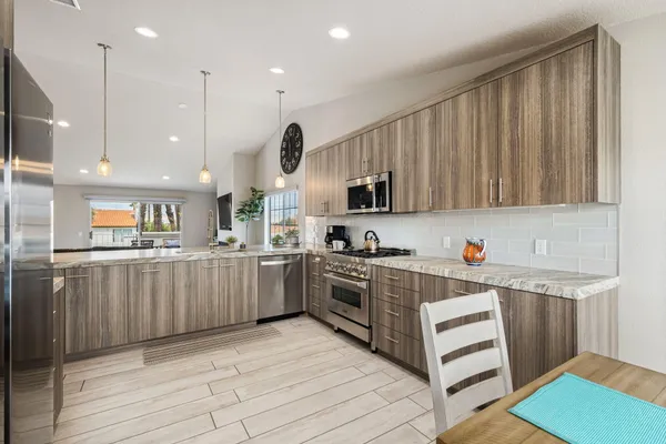 a kitchen with stainless steel appliances granite countertop a refrigerator sink and wooden cabinets