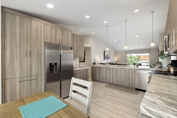 a kitchen with stainless steel appliances granite countertop a refrigerator a sink a stove and a oven