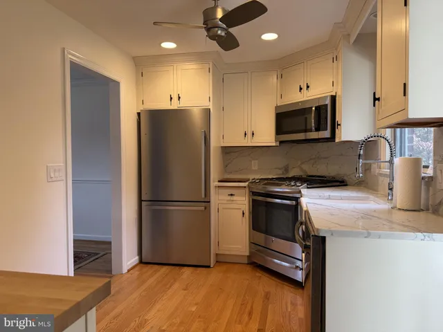 a kitchen with a refrigerator stainless steel appliances wooden floor and cabinets