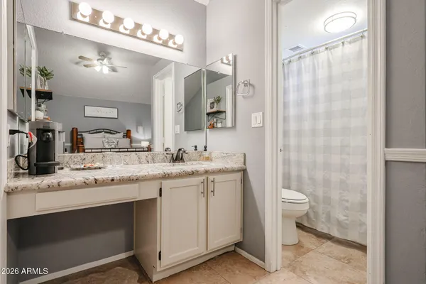 a bathroom with a granite countertop sink a toilet a mirror and shower