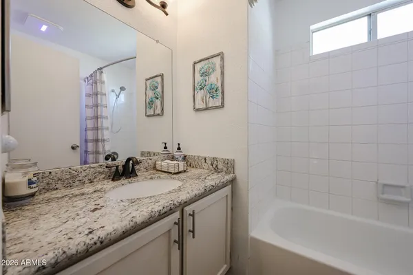 a bathroom with a granite countertop sink a mirror a bathtub and shower