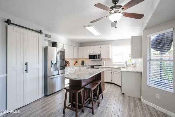 a kitchen with a refrigerator a sink dishwasher a stove and white cabinets with wooden floor