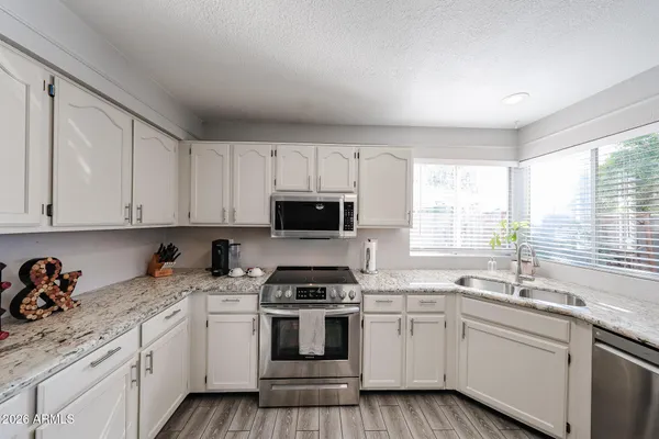 a kitchen with granite countertop white cabinets sink and appliances