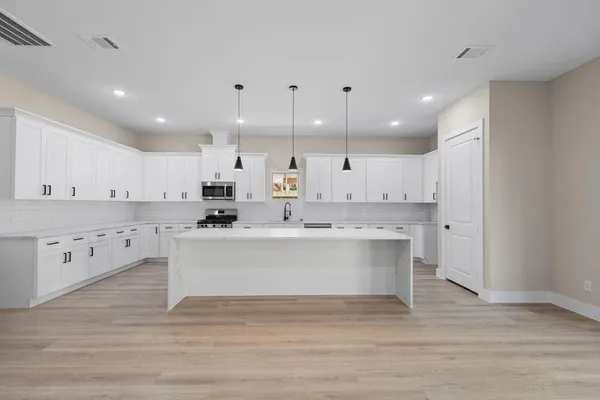 a view of kitchen with kitchen island a sink dishwasher stove with wooden floors